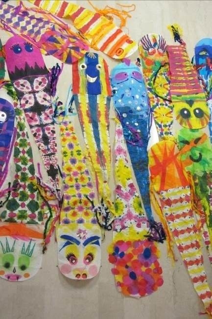 A collection of colorful, handmade fish-shaped paper crafts are displayed on a white surface. Each fish features unique patterns and colors, showcasing creativity and artistry.