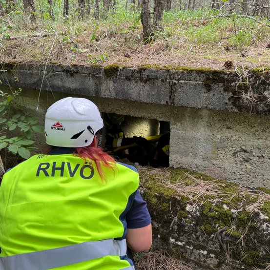 Ein Arbeiter mit weißem Helm und neongrüner Weste inspiziert ein Loch in einer Betonmauer.