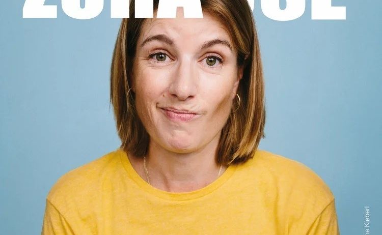 Eine Frau mit kurzen Haaren, die ein gelbes Positano Italy T-Shirt trägt, lächelt in die Kamera vor blauem Hintergrund. Über ihr steht weißer Text 'Willkommen Zuhause'.