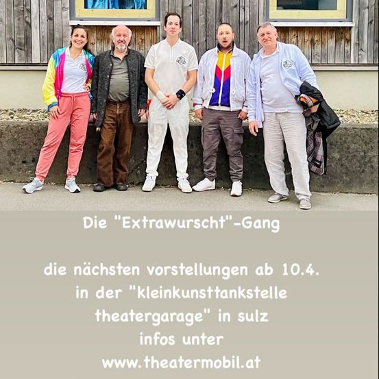 Fünf Personen stehen vor einer Holzwand. Die Gruppe besteht aus zwei Frauen und drei Männern. Sie tragen Freizeitkleidung. Eine trägt eine bunte Jacke. Die Wand hat zwei gerahmte Bilder über ihnen. Ein Text lautet: 'Die Extrawunsch-Gang die nächsten Vorstellungen ab 10.4.'