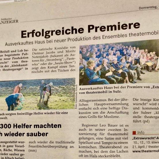 Ein Zeitungsartikel berichtet über die erfolgreiche Premiere einer neuen Produktion des Ensembles theatermobil. Er hebt die satirische Komödie von Dietmar Jacobs und Moritz Netenjakob hervor. Der Artikel zeigt ein Bild des Publikums im Theater und erwähnt die jährliche Versammlung der Alltagsgrassismus.