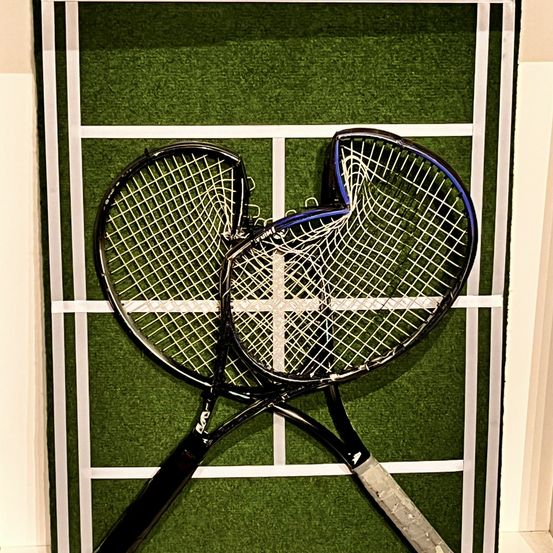 Zwei Tennisschläger sind gekreuzt und gegen ein grünes Feld mit weißen Linien, die einem Tennisplatz ähneln, gelehnt.
