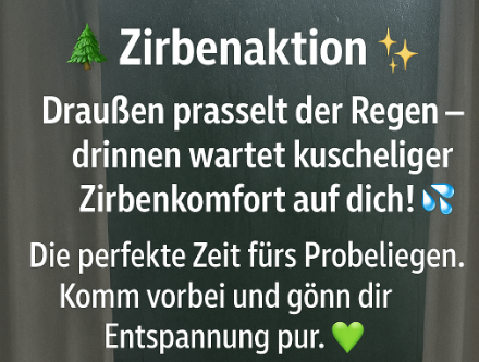 Eine Tafel zeigt 'Zirbenaktion' mit einem Tannenbaum, Sternen und Regentropfen. Es steht geschrieben: 'Draußen prasselt der Regen - drinnen wartet kuschliger Zirbencomfort auf dich!' Darunter steht: 'Die perfekte Zeit zum Faulenzen. Komm vorbei und genieße Entspannung pur.'