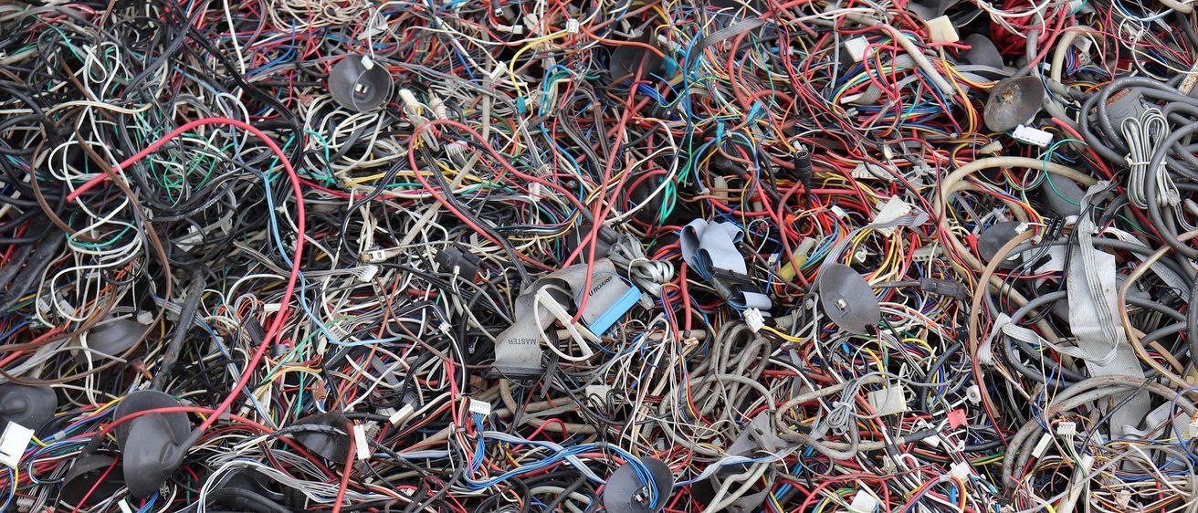 Ein großer Haufen verhedderter Drähte und Kabel in verschiedenen Farben, einschließlich schwarz, rot, blau und gelb, mit einigen sichtbaren Steckverbindern und Komponenten.