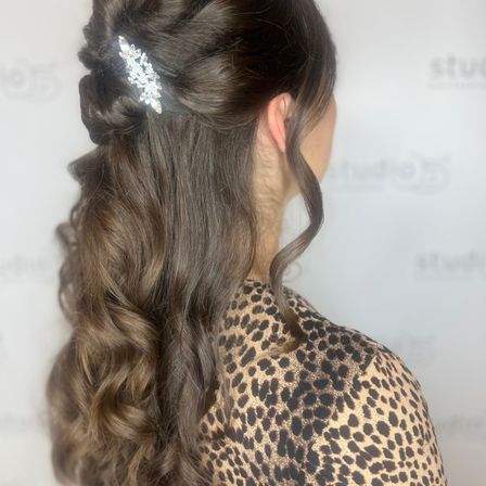 Rückansicht einer Frau mit welligem Haar, das zu einem Dutt gebunden ist, mit einer dekorativen Haarnadel. Sie trägt ein Leopardenprint-Oberteil.