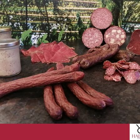 Eine Auswahl verschiedener Würste, einschließlich Salami, Salami-Scheiben und einem Glas Dressing, auf einem Tresen zusammengestellt.