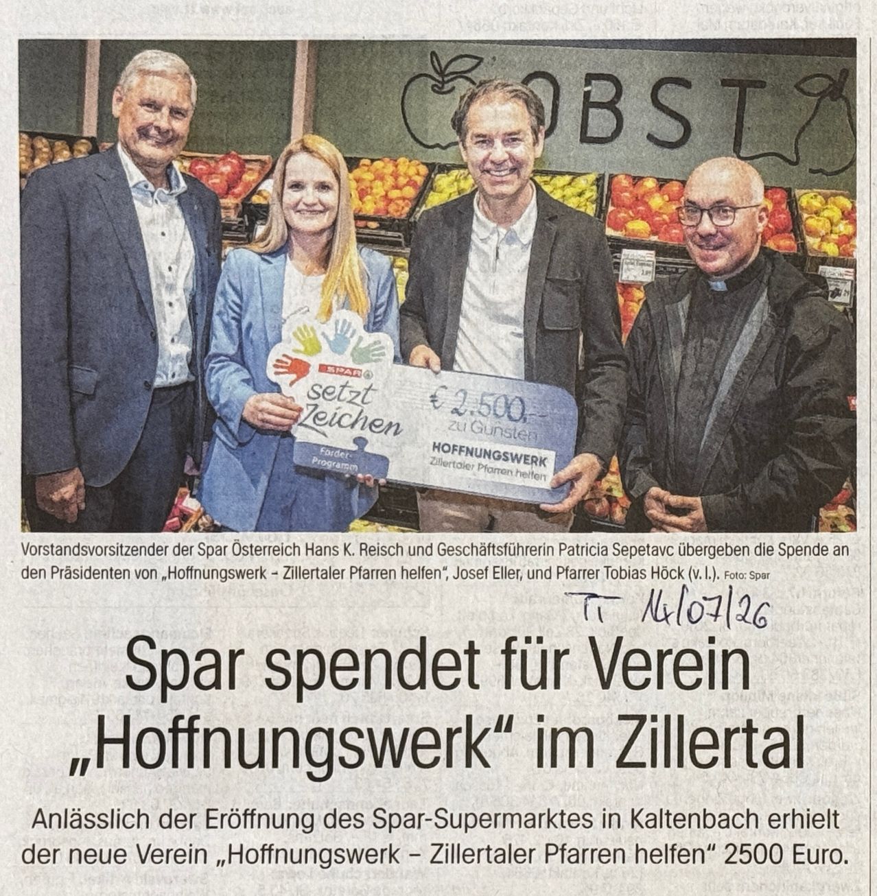 Vier Personen stehen in einem Supermarkt mit einem großen Schild, auf dem 'Spar setzt Zeichen' steht, und halten einen Scheck über 2.500 Euro. Der Mann links hält ein Schild mit 'Spar setzt Zeichen' und die Frau neben ihm hält einen großen Scheck. Der Mann rechts trägt eine Brille und einen schwarzen Mantel.