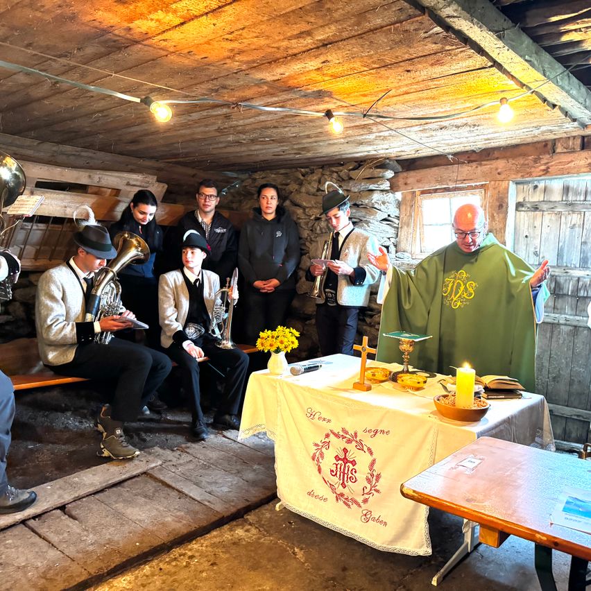Eine Gruppe von Musikern in traditioneller Kleidung versammelt sich um einen Tisch mit Kerze und Blumen, möglicherweise in Vorbereitung auf eine Aufführung.