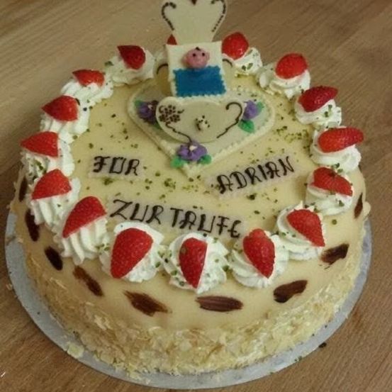 Ein Geburtstagskuchen mit weißer Glasur, verziert mit Erdbeeren und einer kleinen Schweinefigur. Darauf steht 'FUR ADRIAN'.