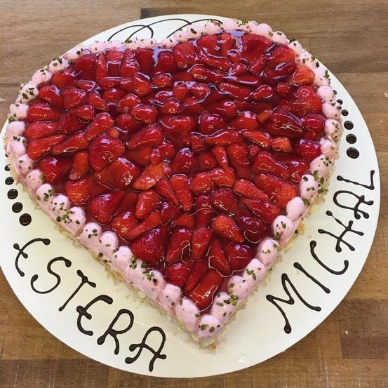 Ein herzförmiger Kuchen gefüllt mit frischen Erdbeeren, mit einer rosa Glasur verziert und mit dem Namen Michael.