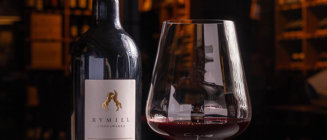 Eine Flasche Rymill Shiraz Wein aus Coonawarra, Jahrgang 2019, mit einem Glas Rotwein auf einem Tisch.