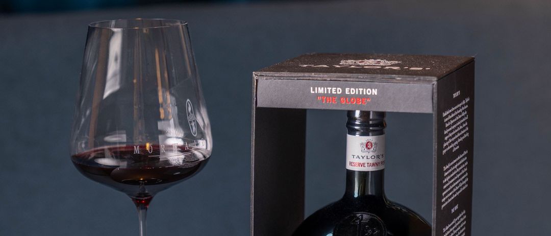 Ein Weinglas gefüllt mit dunklem rotem Wein neben einer schwarzen Box, die 'Limited Edition The Globe' beschriftet ist, mit einer Flasche darin.