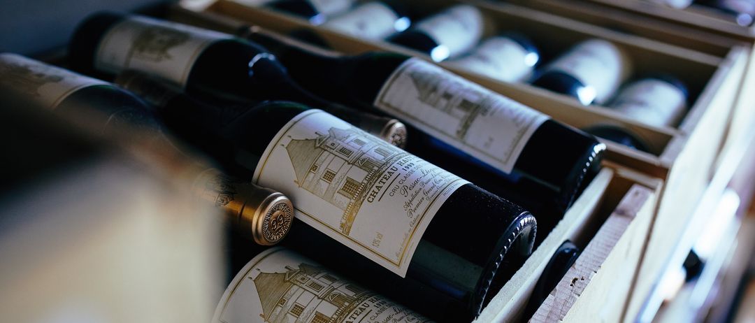 A close-up view of several bottles of Chateau Latour wine in wooden crates, illuminated by a soft light.