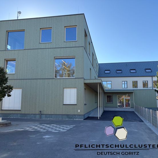 Ein modernes Gebäude mit großen Fenstern und einer Einfahrt vor einem klaren blauen Himmel.