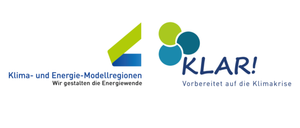 Zwei Logos: 'Modellregionen in die Energiewende' und 'KLAR! Vorbereitet auf die Klima'. Der erste hat ein grünes und blaues Dreieck, der zweite hat drei blaue Kreise und blauen Text.