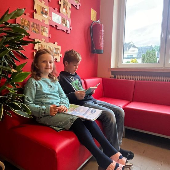 Bild enthält, Person, Sitting, Furniture, Face, Head, Text, Advertisement