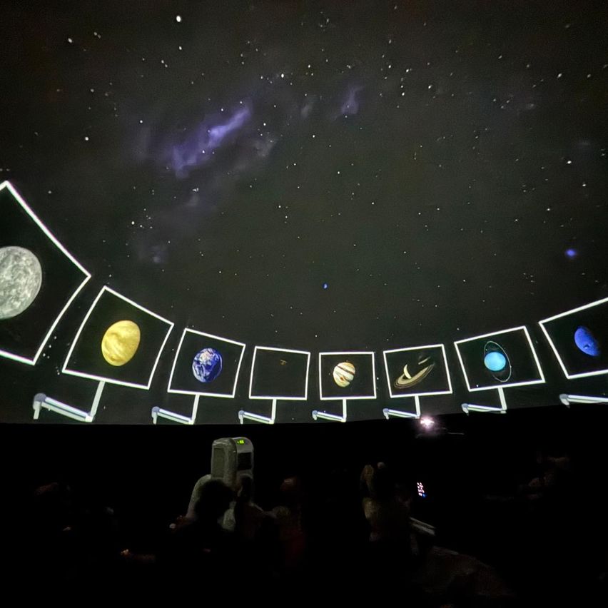 Ein Projektor zeigt Bilder von Planeten in einem dunklen Raum mit einem Sternenhimmel. Acht Planeten sind in Folge zu sehen.
