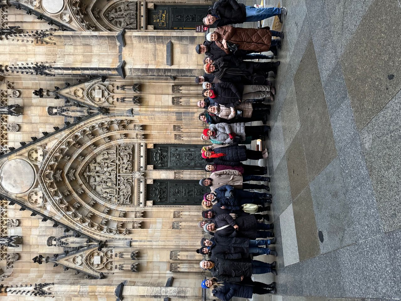 Eine Gruppe von Menschen posiert für ein Foto vor einer gotischen Kathedrale mit kunstvollen architektonischen Details.