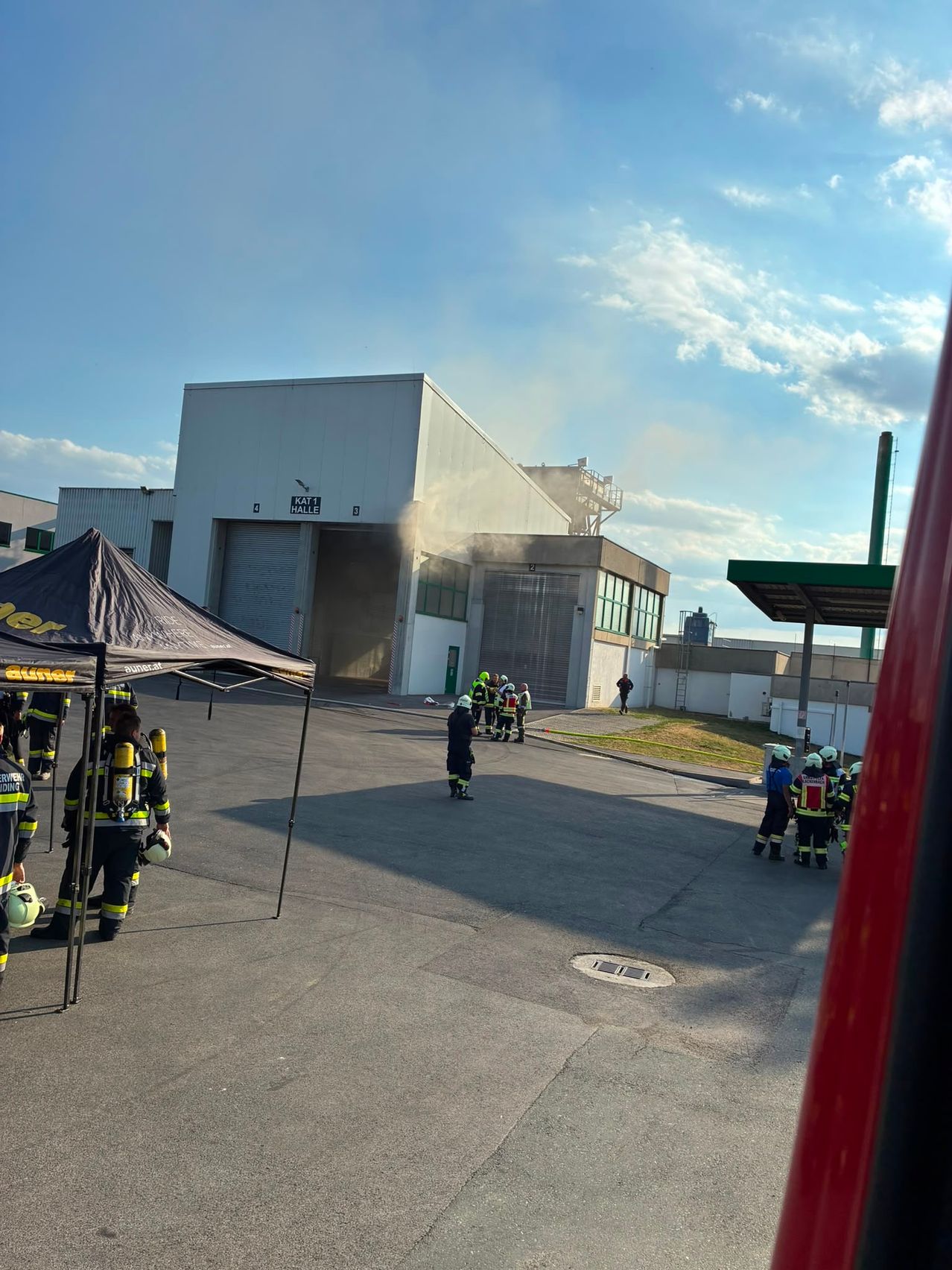 Feuerwehrleute in Schutzkleidung stehen vor einem Gebäude, aus dem Rauch austritt.