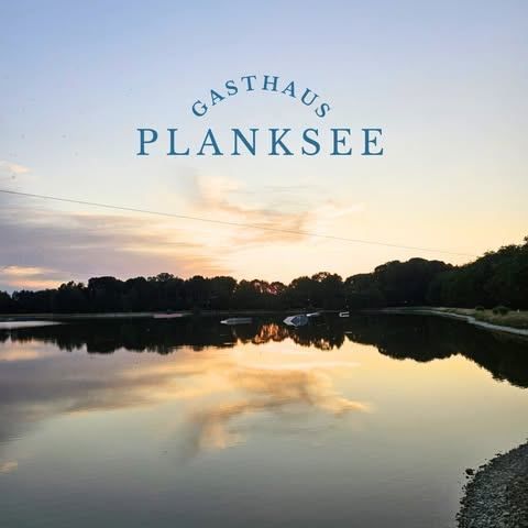 Eine ruhige Ansicht des Planksees mit dem Schriftzug Gasthaus Planksee auf einem klaren Himmelshintergrund. Der See ist ruhig und spiegelt den Himmel und die Bäume wider.