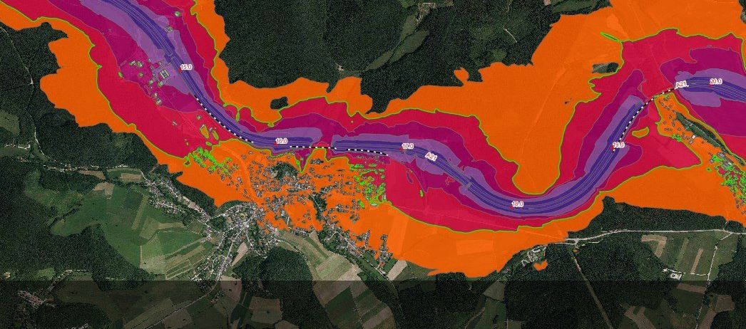 Ein Satellitenbild zeigt einen mäandernden Fluss mit Überschwemmungsgebieten in Lila- und Orangetönen. Grüne Markierungen zeigen städtische Gebiete entlang der Flussufer an.