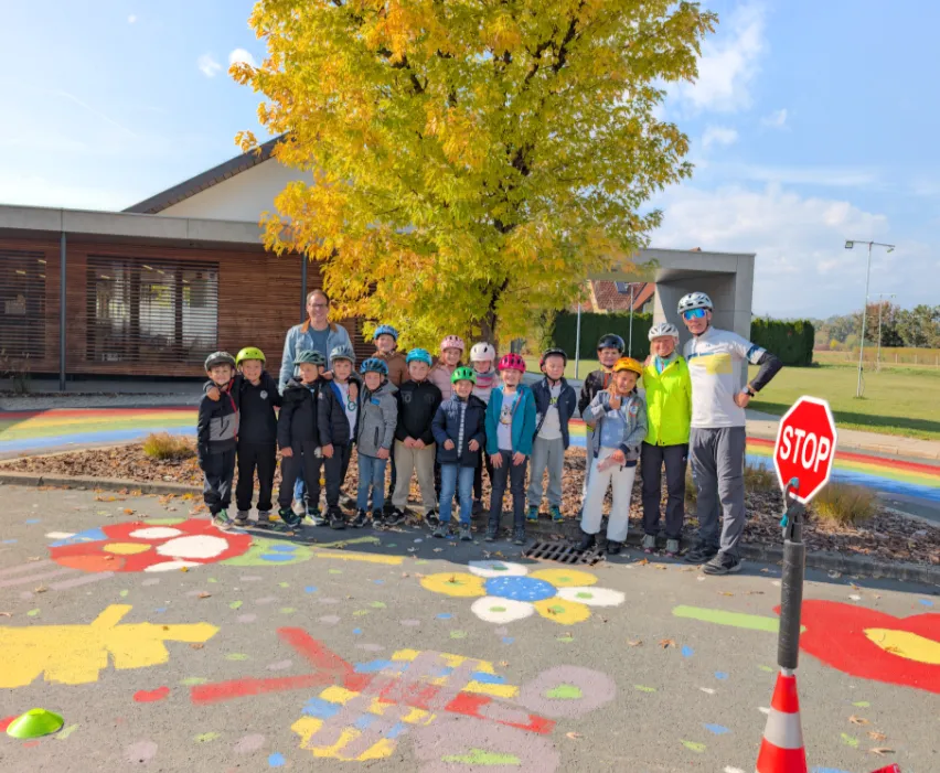 Schulkinder mit Lehrern in Helmposing vor Baum und Schulgebäude