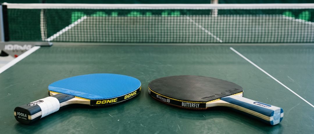 Zwei Tischtennisschläger auf einer Tischtennisplatte