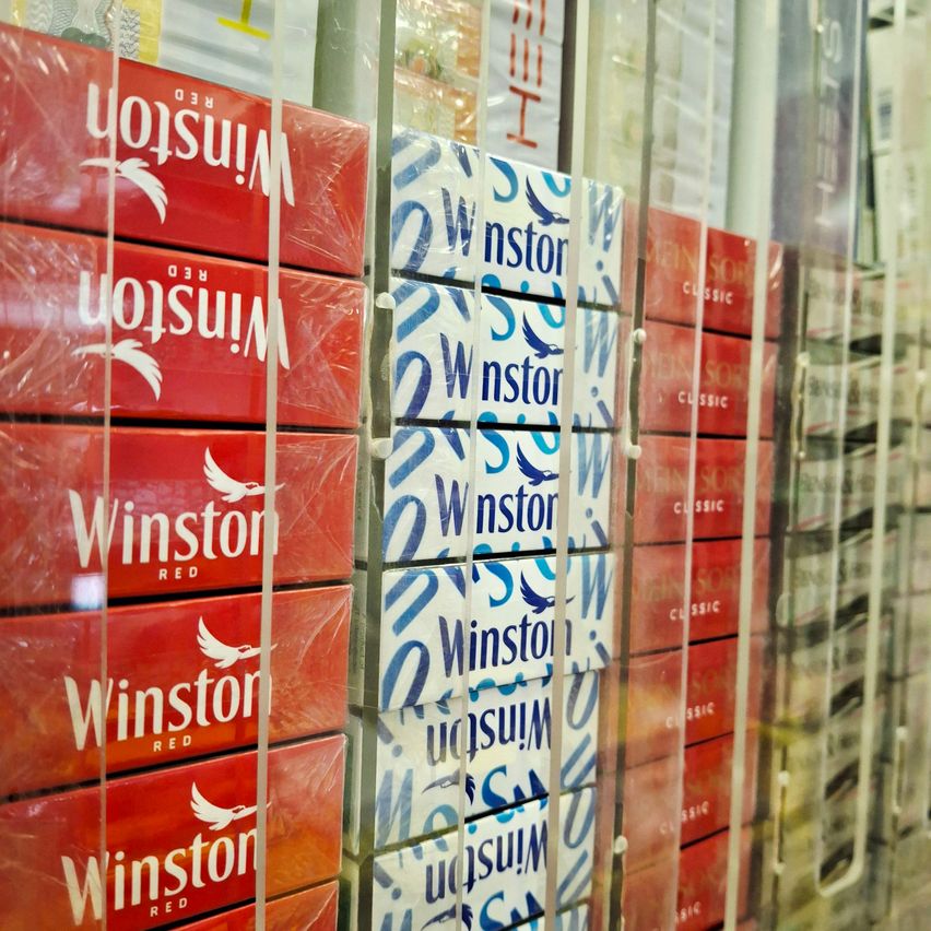 Mehrere rote und blaue Winston Zigarettenschachteln in einer Glasvitrine. Die roten Schachteln haben 'Winston Red' in weiß. Die blauen Schachteln haben 'Winston' in weiß und 'Classic' in blau.