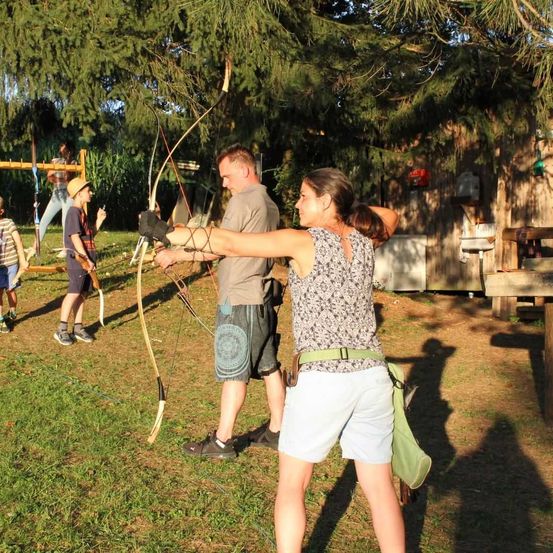 Bild enthält, Shorts, Weapon, Archery, Bow, Person, Archer, Grass, Tree