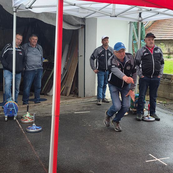 Fünf Männer stehen unter einem roten Zelt, einer von ihnen wirft einen Frisbee.