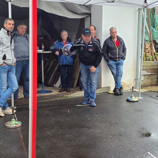 Eine Gruppe von Männern versammelt sich unter einem weißen Zelt. Ein Mann wirft einen Frisbee, während andere zusehen.