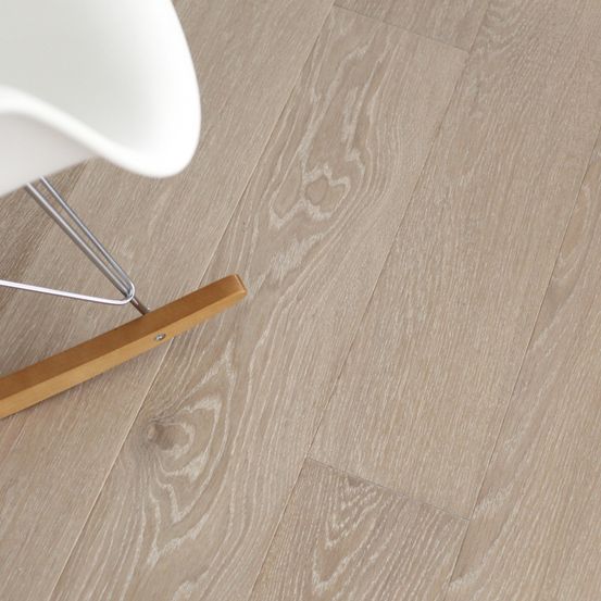 Nahaufnahme eines hellbeigen Holzbodens mit einem weißen Stuhl in der Ecke.