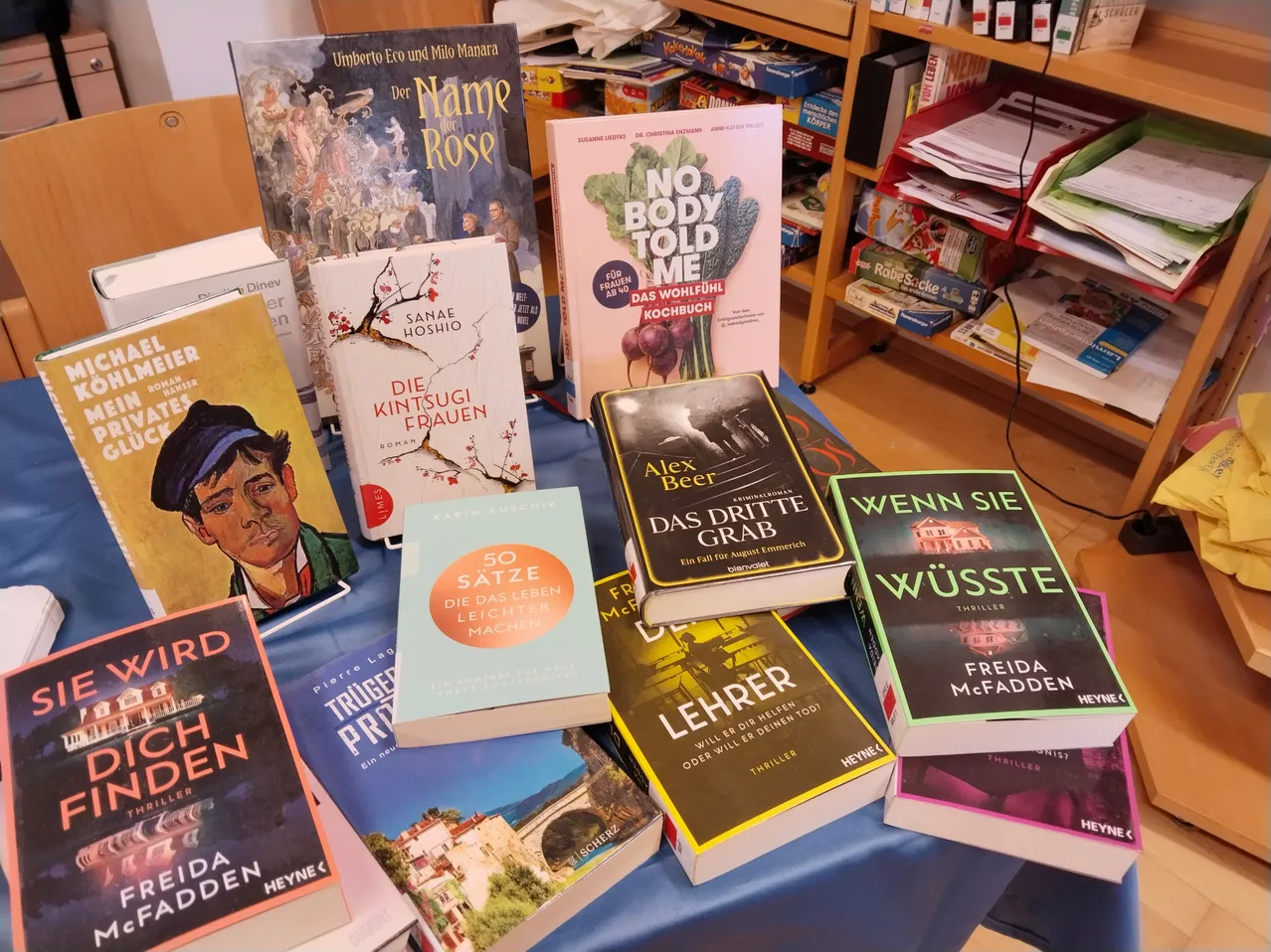 Ein Tisch voller Bücher in einem Buchladen, darunter Titel wie 'Der Name der Rose' und 'No Body Told Me'.