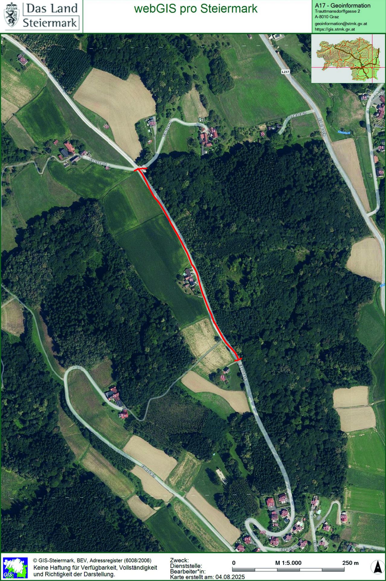 Luftaufnahme eines ländlichen Gebiets mit einer kurvenreichen Straße und mehreren Häusern. Eine rote Linie markiert einen Pfad. Die Landschaft ist mit grünen Feldern und dichten Bäumen gespickt.