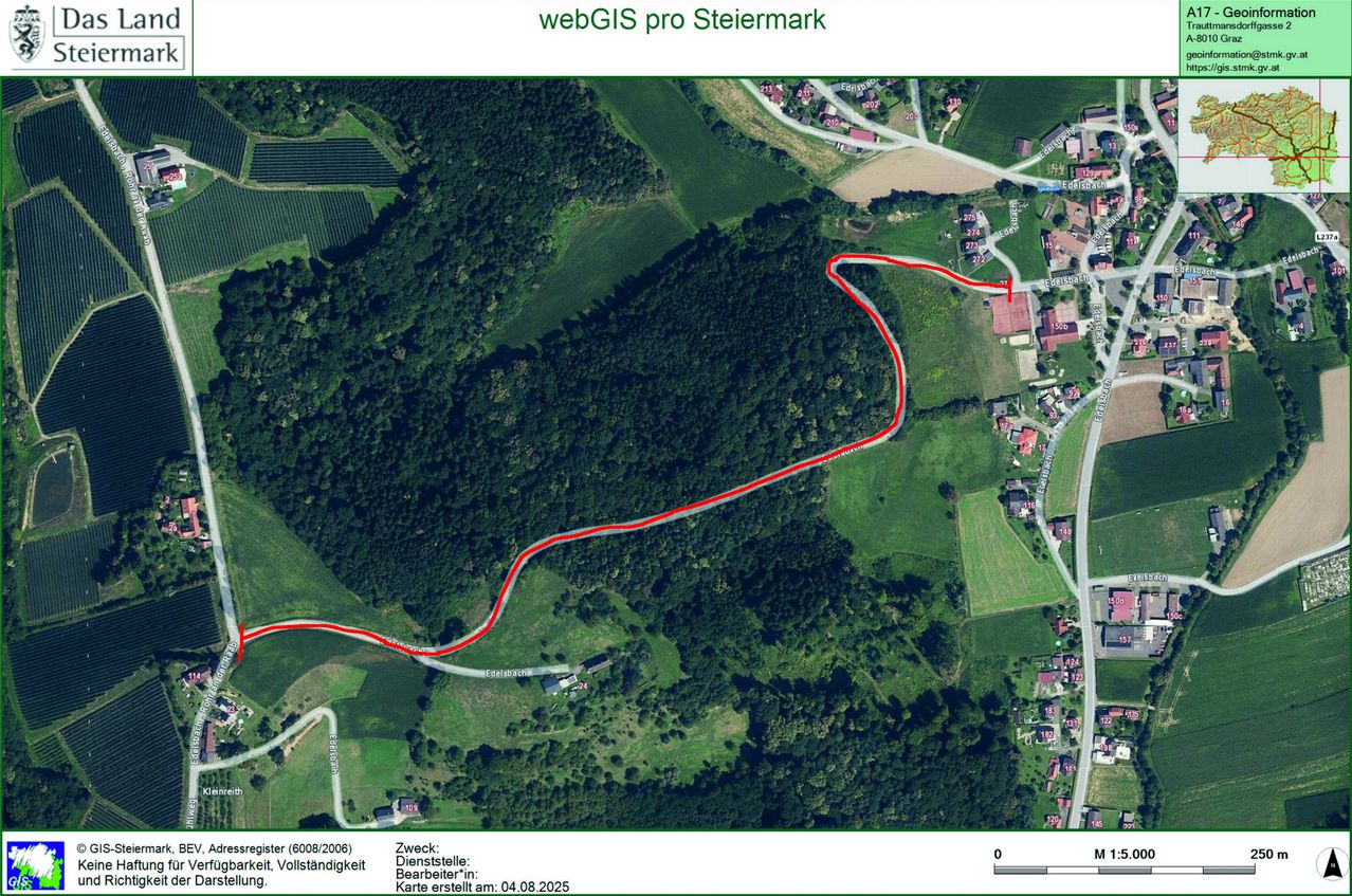 Luftbild einer grünen Landschaft mit einer sich windenden roten Linie, die einen Weg oder eine Route anzeigt. Das Bild zeigt ein ländliches Gebiet mit Häusern, Straßen und landwirtschaftlichen Feldern.