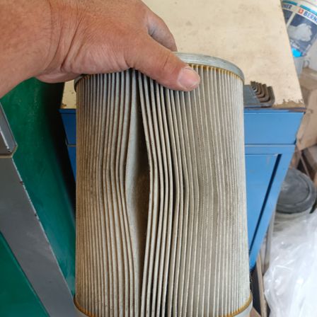 Eine Person hält einen alten zylindrischen Luftfilter mit einem Metallring oben und einem gefalteten Papierfilter im Inneren.