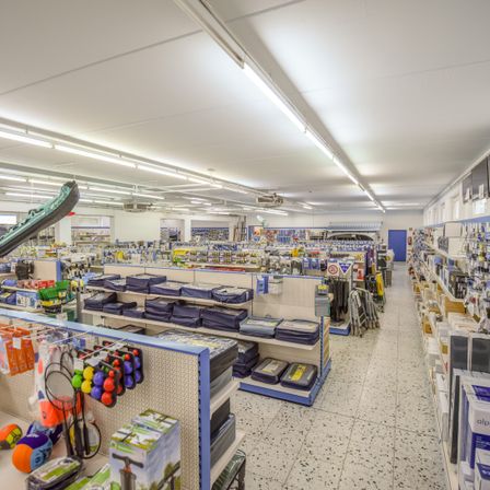 Ein Geschäft mit verschiedenen Artikeln wie Sportgeräten und Aufbewahrungsboxen. Helle Deckenbeleuchtung beleuchtet die Regale.