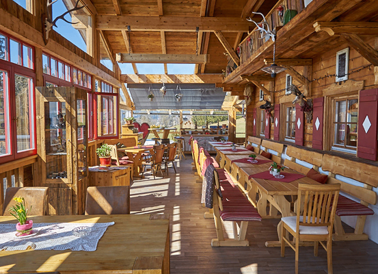 Ein hölzerner Innenraum eines Restaurants mit Holztischen und Stühlen, roten Fenstern und hölzernen Dekorationen.