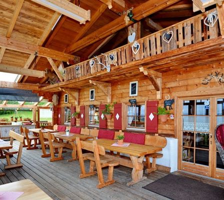 Ein Holzrestaurant mit Holztischen, Stühlen und einer Terrasse mit Pflanzen und einem herzförmigen Dekor.