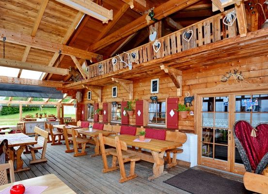 Ein Holzrestaurant mit Holztischen, Stühlen und einer Terrasse mit Pflanzen und einem herzförmigen Dekor.