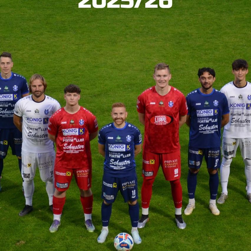 Das Fußballteam posiert für ein Mannschaftsfoto auf dem Spielfeld, in Trikots mit verschiedenen Sponsoren. Die Worte 'Kampfmannschaft 2025/26' sind oben deutlich zu sehen.