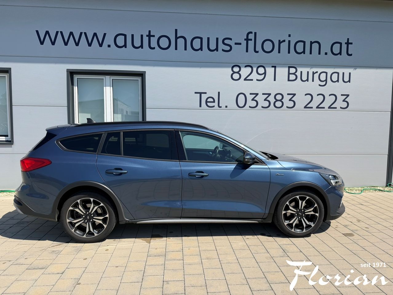Ein blaues Ford-Auto steht vor einem Gebäude mit der Website www.autohaus-florian.at und einer Telefonnummer.