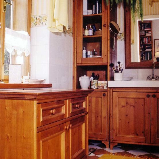 Ein Badezimmer mit Holzschränken und gefliesten Wänden, mit einem Spiegel, einem Regal mit persönlichen Gegenständen und einem Waschbecken.