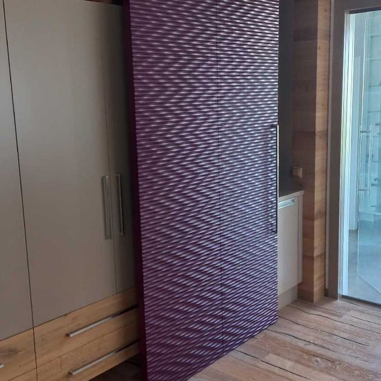 Ein modernes Zimmer mit Holzboden, einer großen Schiebetür und einer gemusterten lila Wand mit weißem Rand.