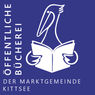Ein blauer Hintergrund zeigt einen weißen Vogel, der ein Buch liest. Der Vogel hat ausgebreitete Flügel und hält das Buch offen. Der Text lautet 'öffentliche Bucherei der Marktgemeinde Kittsee'.