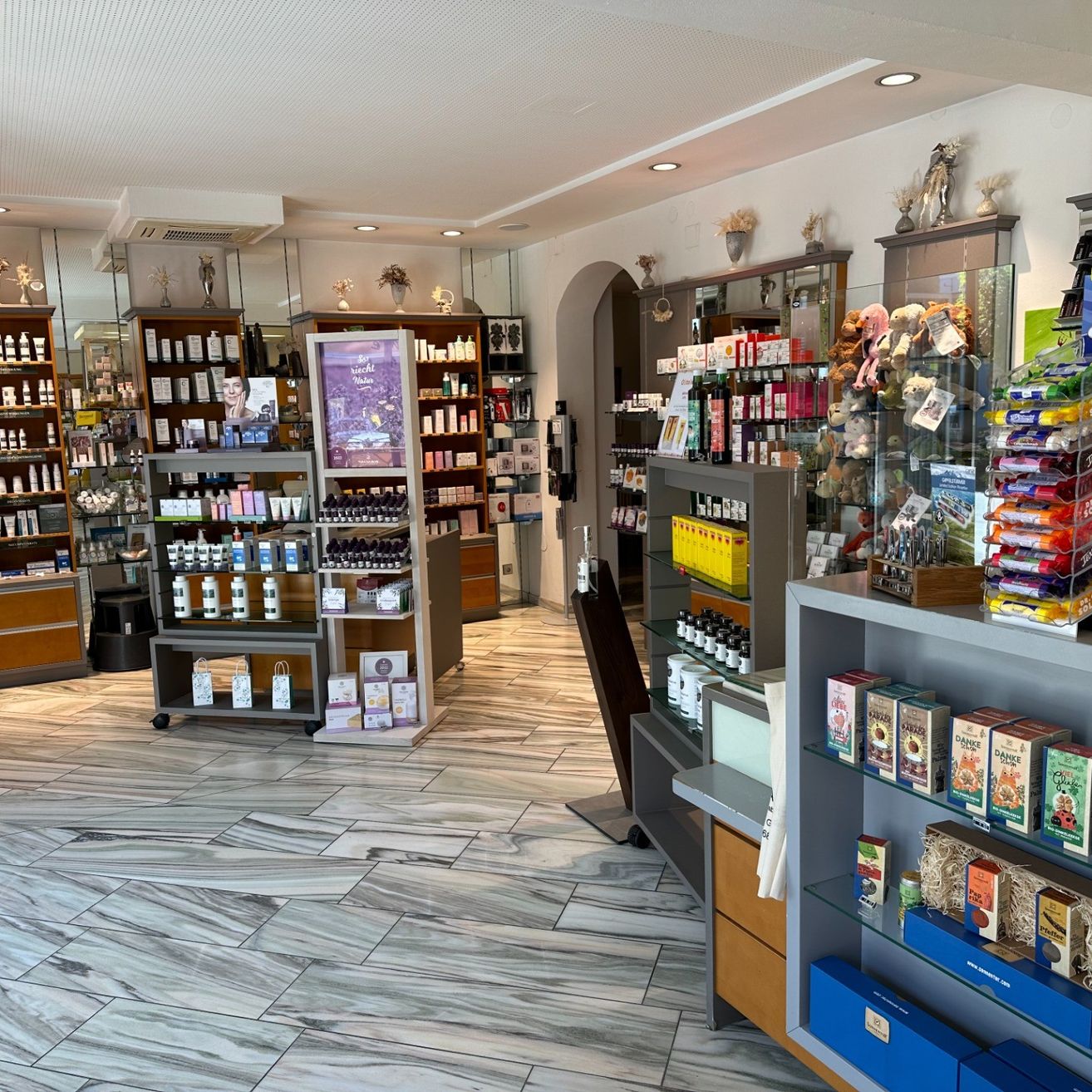 Das Innere eines Ladens mit Holzböden und Regalen, die verschiedene Produkte enthalten. Die Regale sind mit Flaschen, Schachteln und Artikeln mit Etiketten gefüllt. Ein Monitor ist an einem der Regale montiert.