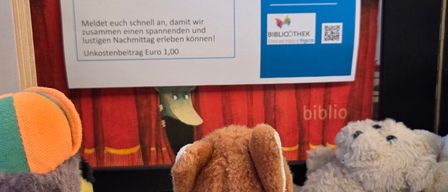 Ein Plakat lädt Kinder zu einer Bibliotheksveranstaltung am 18. Juni von 15-16 Uhr ein. Ein Eintrittspreis von 1 Euro ist erforderlich. Plüschtiere sind im Vordergrund sichtbar.