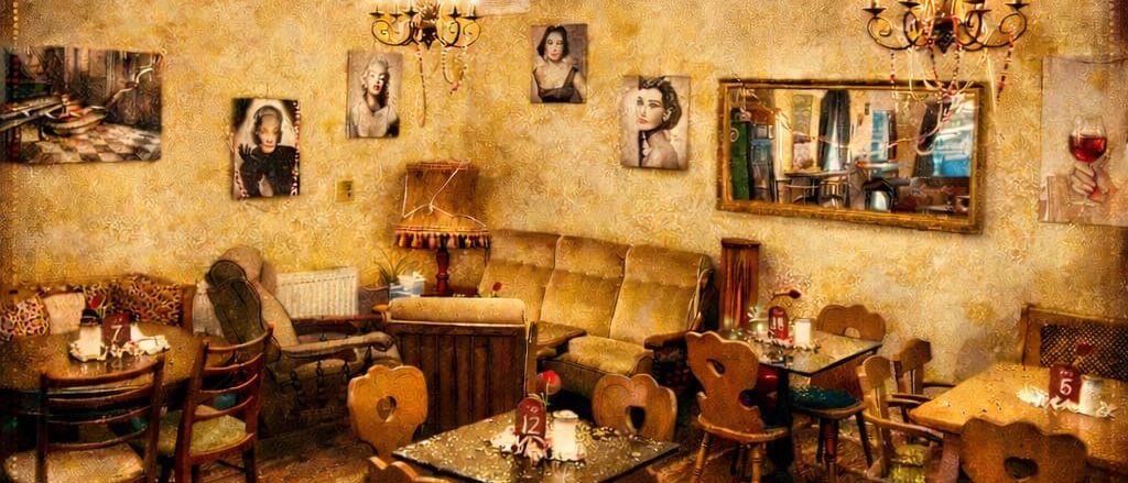 Werbeposter für Cafe Vintage in der Kehrgasse 41 in Trofaiach. Das Bild zeigt ein gemütliches Vintage-Cafe-Interieur mit Tischen und Stühlen, roten Äpfeln auf dem Boden und Vintage-Dekorationen an der Wand.