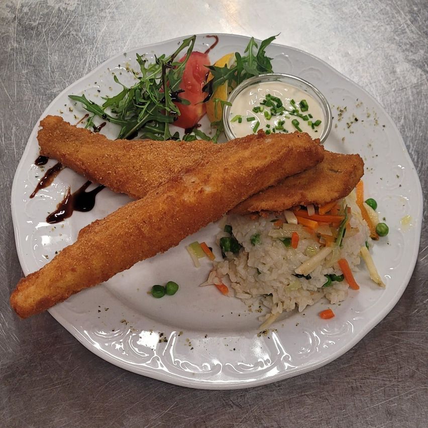 Ein weißer Teller mit zwei frittierten Fischstäbchen, Salat und Reis. Es gibt auch eine kleine Schüssel Sauce.