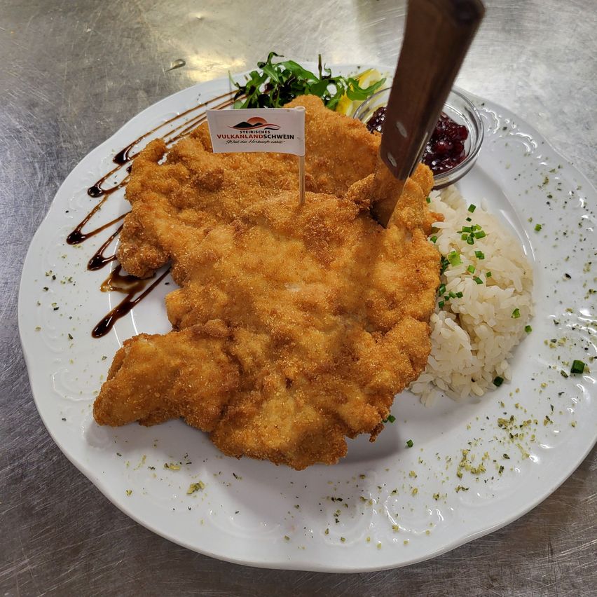 A plate of crispy fried chicken with rice and a small bowl of cranberry sauce.